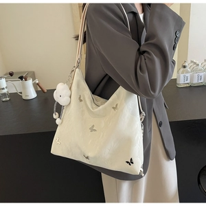 Dettaglio della borsa tote beige con stampa a farfalla e ciondolo a nuvola in interni