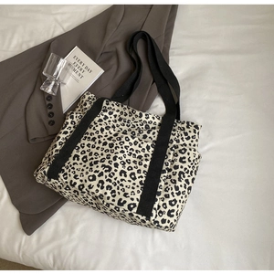 Detalle del bolso tote de lona con estampado de leopardo, asas negras y bolsillo lateral