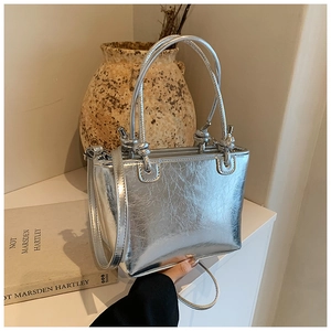 Close-up of silver textured bucket bag with knotted handles and a minimalist artistic vibe