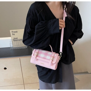 Detail of pink faux leather crossbody bag with plaid pattern on modern interior background