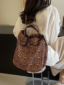 Grande borsa tote in tela con stampa leopardata e tracolla nera su modella donna