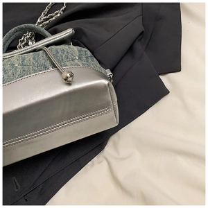 Détail du sac patchwork en denim bleu et cuir argenté avec fermoir orbe et chaîne