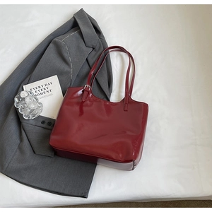 Detail view of smooth wine red leather tote bag texture and thin shoulder straps