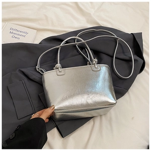 Detail of silver bucket bag with pleated metallic finish and knotted strap design