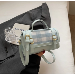 Detail of mint blue handbag featuring plaid fabric texture and metal buckle straps