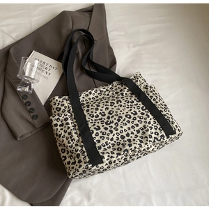 Vista detallada del bolso tote de lona con estampado de leopardo y correas negras sobre tela
