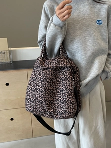Borsa tote in tela leopardata alla moda con tracolla regolabile indossata da una modella