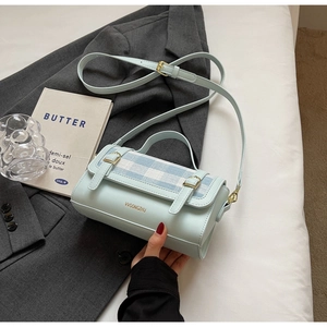 Detail of mint blue PU leather crossbody bag with blue and white plaid flap on a suit