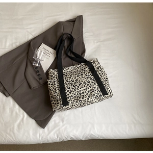 Vista detallada de un bolso tote de lona con estampado de leopardo y bolsillos laterales