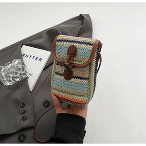 Detail of rainbow striped straw crossbody bag with leather trim and horn buckle closure
