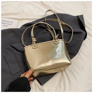 Detailed view of glossy golden bucket bag with metallic texture and thin strap