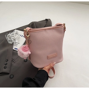 Pink pleated bucket bag with gold hardware and knit hat pompom charm detail