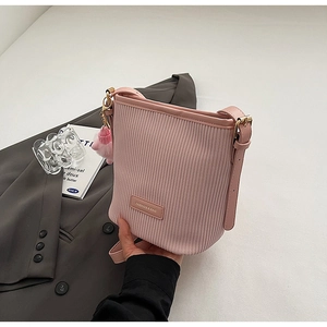 Detail of pink pleated bucket bag featuring a soft plush ball charm and gold hardware