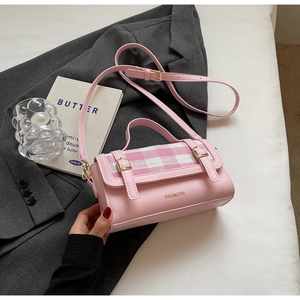 Close-up of pink checkered flap bag with golden buckles on a stylish textured background