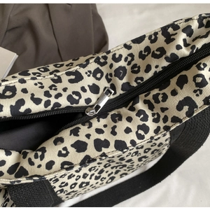 Detalle de bolso tote de lona con estampado de leopardo, cremallera y textura de tela