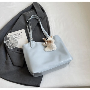 Detail of light blue tote bag with glossy leather texture and white bear charm