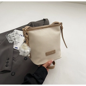 Close-up of pleated bucket bag with brown leather label and cute plush sheep charm