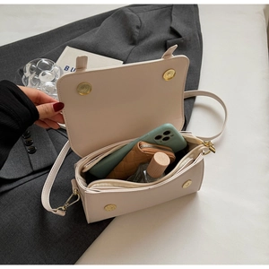Internal storage detail of cream rectangle crossbody bag with zipper and dual magnetic buckles