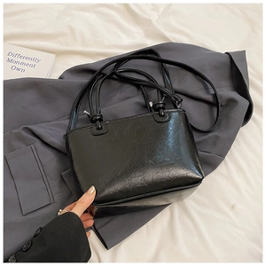 Close-up of black glossy bucket bag with wrinkled leather texture and dual straps