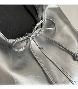 Close-up of silver metallic bucket bag with crumpled texture and drawstring bow detail