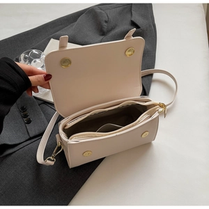 Interior view of cream crossbody bag showing multi-compartment storage and gold hardware