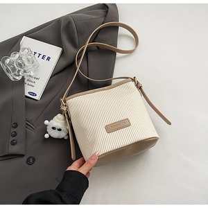 Detail of pleated beige corduroy bucket bag with khaki leather base and plush charm
