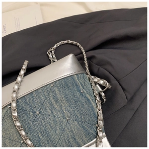 Détail du sac bandoulière en denim bleu avec coutures matelassées et chaîne argent