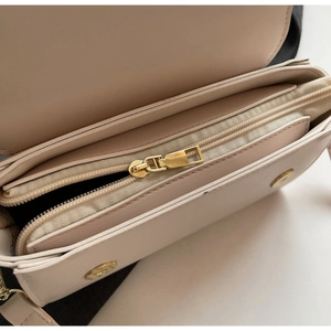Detailed interior of color-block flap bag showing zipper pocket and gold hardware