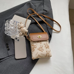 Detail der Umhängetasche mit Teddybär-Print, goldenem Drehverschluss und braunem Gurt