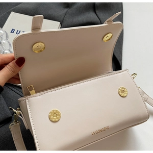 Detail view of the cream crossbody bag interior with gold magnetic buckles and zipper pocket