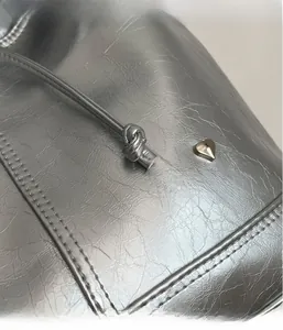 Detailed macro view of silver metallic textured fabric with heart charm and stitching