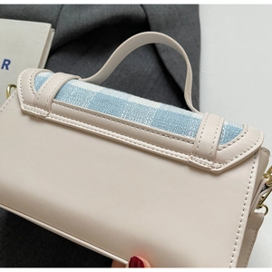 Detail of cream leather handbag featuring blue checkered fabric and gold metal hardware