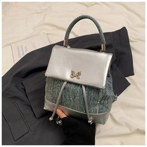 Détail du mini sac à dos en PU argenté et denim avec boucle papillon et matelassage chic