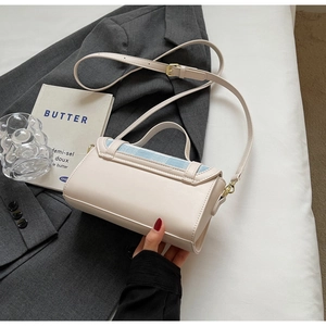 Detail of cream leather handbag featuring a light blue plaid flap and gold hardware