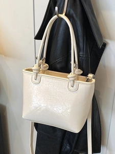 Chic cream white bucket bag with knotted handle and glossy patent leather finish