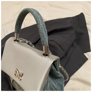 Détail du sac à bandoulière en jean bleu avec boucle papillon argentée