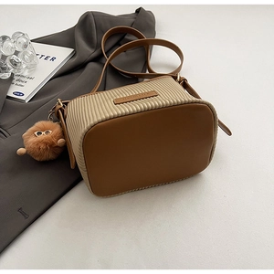 Detail of pleated bucket bag featuring contrast colors and a plush sunglasses charm