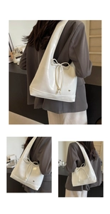 Detail of silver metallic hobo bag featuring glossy finish and elegant bow with heart charm