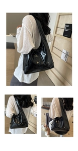 Detail of black glossy leather tote bag featuring a decorative bow and heart logo