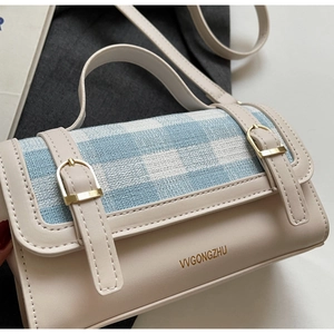 Detail view of the beige and blue plaid fabric texture with gold metallic buckle accents
