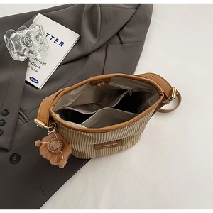 Detail view of khaki corduroy bucket bag with multi-layer interior and plush charm