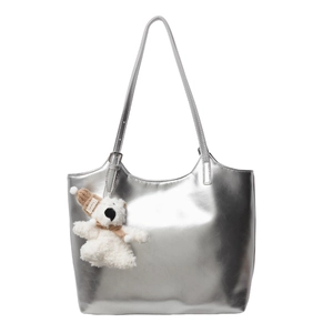 Metallic silver tote bag with mirror finish and white plush bear charm on long shoulder straps