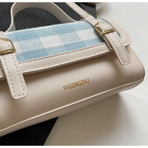 Detail showing high-quality faux leather texture and blue plaid pattern with gold hardware