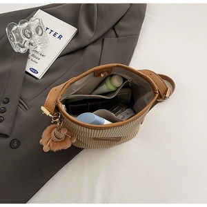 Top view of brown corduroy bucket bag showing multi-pocket interior and plush bear charm