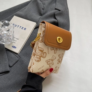 Details kleiner Umhängetasche in Creme und Braun mit Bärenprint und goldenem Verschluss