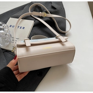 Detail of cream crossbody bag with light blue plaid fabric and golden metal logo