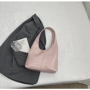 Detail shot of a light pink high-gloss Hobo shoulder bag with a wide strap on a white fabric