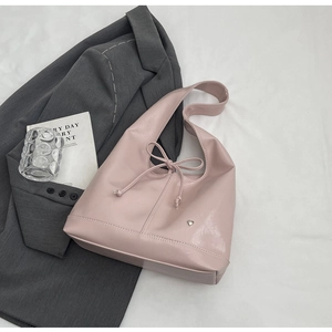 Close-up of light pink PU leather bag with bow detail and heart metal plaque