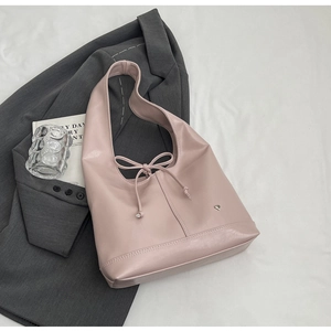 Close-up of pink leather tote bag featuring a bow tie design and silver heart emblem