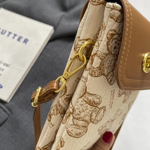 Detail des goldenen Drehverschlusses und des geprägten Leders der Teddybär-Handytasche
